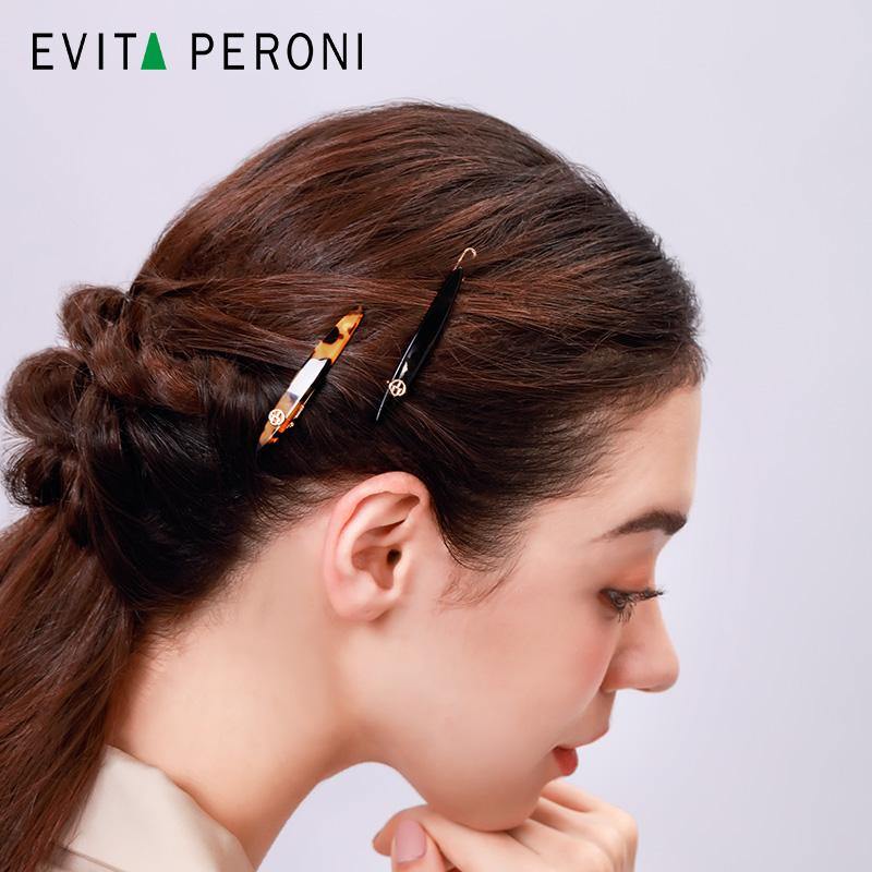 Woman with brown hair wearing tortoiseshell and black hair barrettes, side profile